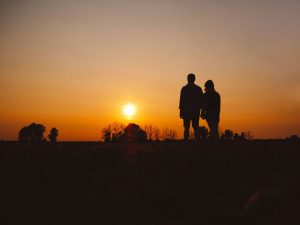 Familie Hand in Hand als Silhouette bei Sonnenuntergang