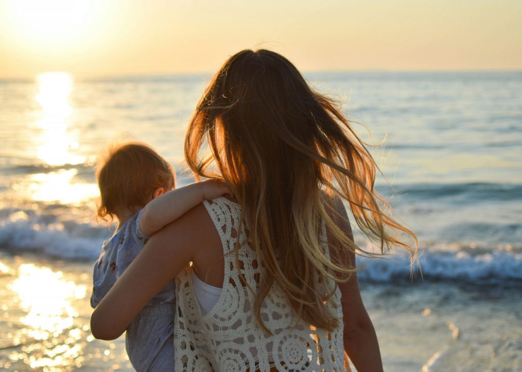 Frau mit Kind auf dem Arm am Meer, Nähe und Verbundenheit zwischen Eltern und Kind