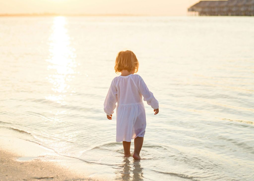 Kleines Kind läuft am Strand Richtung Meer, Sicherheit und Orientierung im Familienalltag