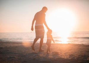 Vater mit seinen Kindern am Strand bei Sonnenuntergang, Familienbegleitung und Bindung
