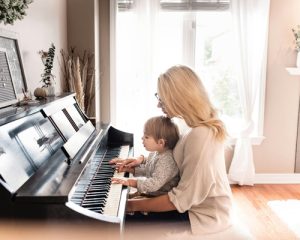 Mutter sitzt mit Kind am Klavier