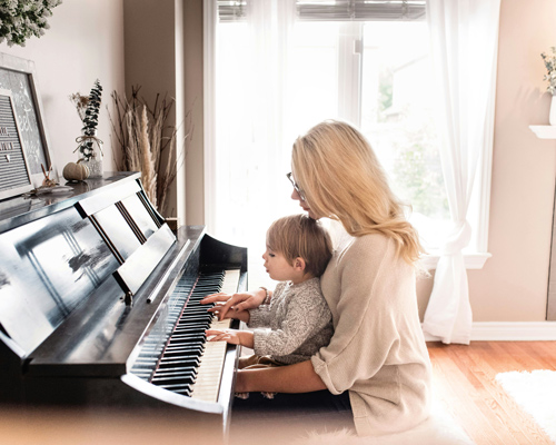Mutter sitzt mit Kind am Klavier