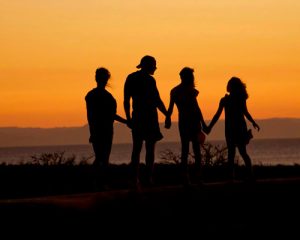 Familie Hand in Hand beim Sonnenuntergang